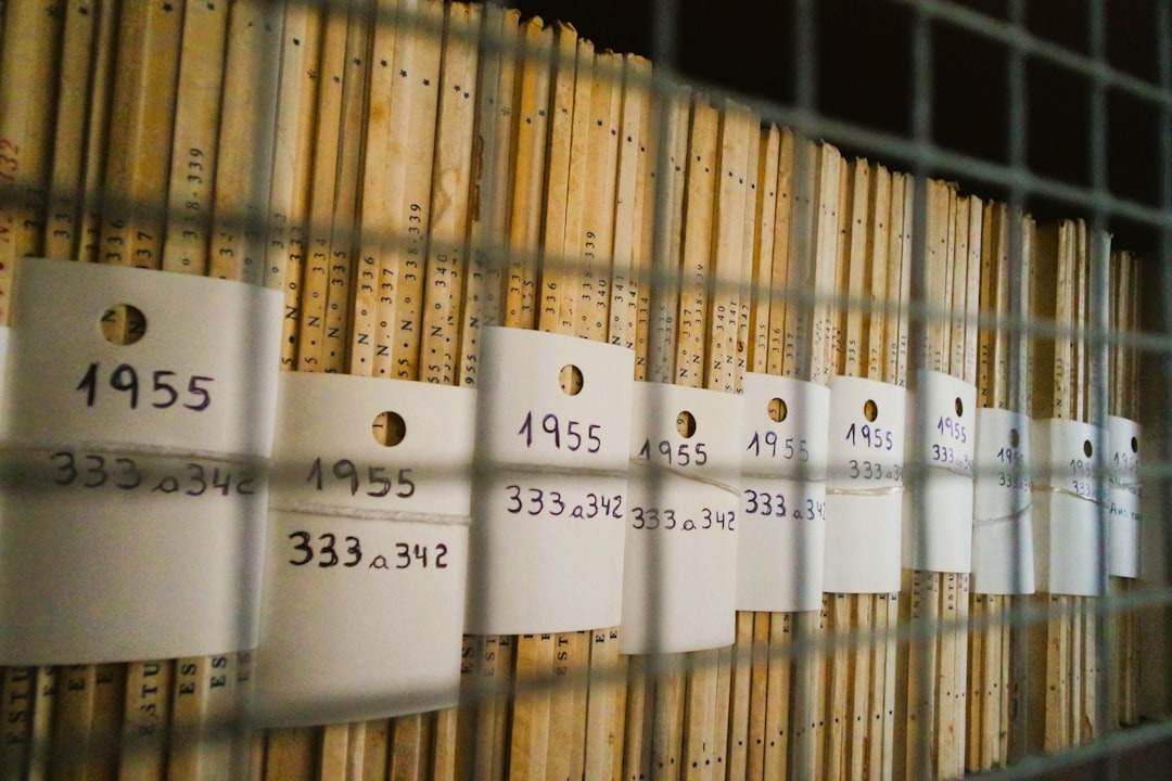 Archival documents stacked behind wire mesh with dated tags.